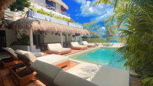 巴卡拉爾的住宿－Hotel Sun Ha Bacalar，一个带白色椅子的游泳池,一个度假村
