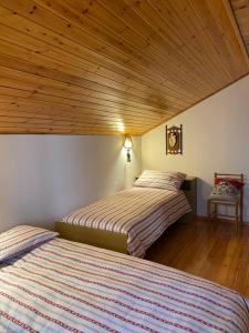 2 Betten in einem Schlafzimmer mit Holzdecke in der Unterkunft Valsugana, Lagorai, Laghi, Arte Sella in Rundscheinberg