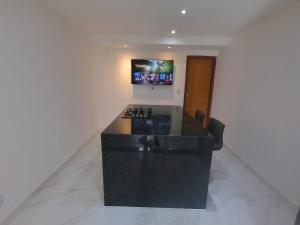 uma cozinha com um balcão preto e uma televisão na parede em TH 101 - Flat com Banheira de Hidromassagem em Governador Valadares