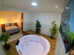 a large bath tub in a room with potted plants at TH 101 - Flat com Banheira de Hidromassagem in Governador Valadares