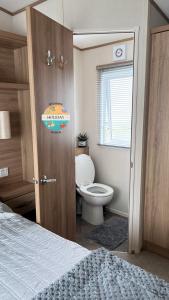 ein Bad mit einem Bett, einem WC und einer Tür in der Unterkunft Field View - Martello Beach - Sylwia's Holiday Homes in Jaywick Sands