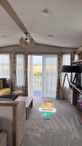 ein Wohnzimmer mit einem Sofa und einem Tisch in der Unterkunft Field View - Martello Beach - Sylwia's Holiday Homes in Jaywick Sands