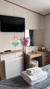a bedroom with a mirror and a bed with towels at Field View - Martello Beach - Sylwia's Holiday Homes in Jaywick Sands