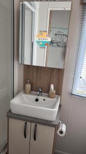 ein Badezimmer mit einem weißen Waschbecken und einem Spiegel in der Unterkunft Field View - Martello Beach - Sylwia's Holiday Homes in Jaywick Sands