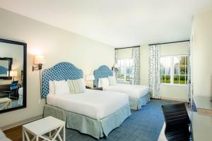 a hotel room with two beds and a mirror at The Inn by Sea Island in Saint Simons Island