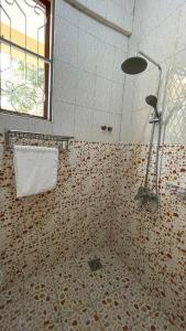 y baño alicatado con ducha y ventana. en Skill forest lodge en Arusha