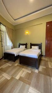 two beds in a room with wooden floors at Skill forest lodge in Arusha