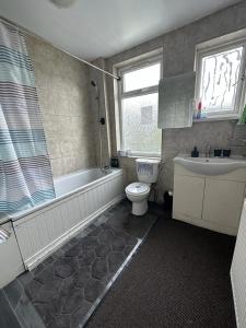 a bathroom with a tub and a toilet and a sink at Affordable Private Rooms in Wembley in London