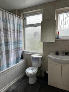 a bathroom with a toilet and a sink and a window at Affordable Private Rooms in Wembley in London