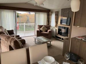 a living room with a couch and a television at Staycay Luxury Caravan in Seasalter