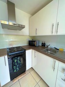 a kitchen with white cabinets and a stove and a sink at The Ultimate Home Away from Home in Birmingham