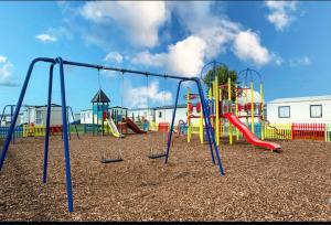 an empty playground with a slide and swings at Staycay Luxury Caravan in Seasalter