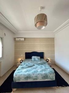 a bedroom with a bed with a blue comforter at cosy et spacieux, avec balcon in Ariana