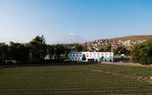 ein weißes Gebäude auf einem Feld mit einem Berg im Hintergrund in der Unterkunft BTH Hotel Arequipa Lake in Arequipa