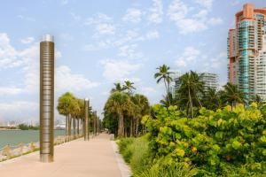 a sidewalk next to the water with palm trees and buildings at Sonder The Deco in Miami Beach