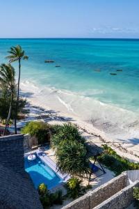 una piscina junto a una playa con el océano en Bitcoin Beach Hotel Zanzibar en Pingwe