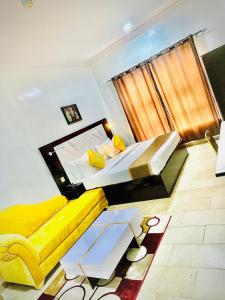 Posh Hotel and Suites Ikeja في إيكيجا: غرفة نوم بسرير اصفر واريكة صفراء