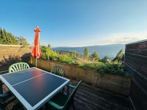 a table and chairs on a balcony with an umbrella at Almblick in ruhiger Lage in Trahütten