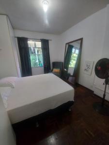 Un dormitorio con una gran cama blanca y una ventana en Quarto tranquilo e familiar no leblon - Quiet family room in leblon, en Río de Janeiro