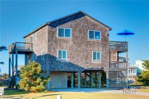 a large brick house with a balcony and an umbrella at 6058 - Are U Shore by Resort Realty in Nags Head