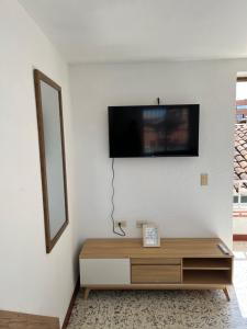 a living room with a tv on a white wall at Casa Blanca Hostal in Rionegro
