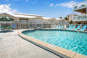 a swimming pool with blue chairs and a building at Private Beach Access With Pool and 2-MIn Walk to Beach in Gulf Shores