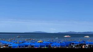 a beach with blue umbrellas and people in the water at Hausemaremma 1 camera in Follonica