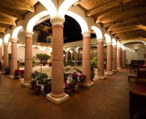 ein großes Gebäude mit Säulen und Topfpflanzen in der Unterkunft Hotel Casa de Familia de San Cristobal in San Cristóbal de las Casas