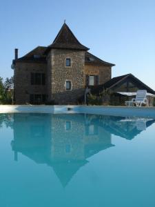 a villa with a swimming pool in front of a house at Hotel La Bastie d'Urfé in Naussac