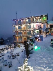 un gran edificio en la nieve con luces en Bhurban View Apartments, en Murree