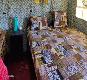 a bed with a quilt on it in a room at Camping Huts at Lord Shiva Camps in Sari