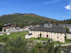 un grand bâtiment blanc sur une colline avec un village dans l'établissement Résidence les deux Nestes, à Arreau