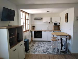 une cuisine avec des placards blancs et une table en bois dans l'établissement Résidence les deux Nestes, à Arreau