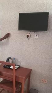 un televisor colgado en una pared junto a una mesa de madera en Amarula Tree Hotel, en Mikumi