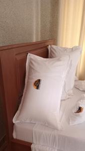 Una cama con sábanas blancas y almohadas con un cartel. en Amarula Tree Hotel en Mikumi