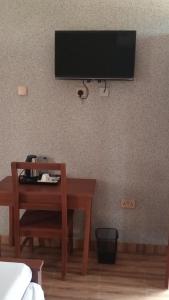 Habitación con escritorio y TV en la pared. en Amarula Tree Hotel en Mikumi