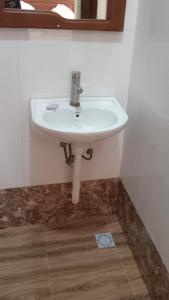 ein weißes Waschbecken im Bad mit Spiegel in der Unterkunft Amarula Tree Hotel in Mikumi
