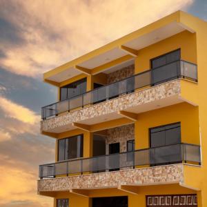 a yellow building with a sunset in the background at ECOLETRAS APART - SÃO THOMÉ DAS LETRAS Mg in São Thomé das Letras
