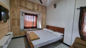 a small bedroom with a bed and a window at Sandiago Villa 2 Bhk House - Only Bachelors Adults in Ooty +4 photos
