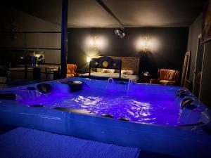 uma grande banheira azul num quarto com uma cama em Loveroom avec jacuzzi 01 em Chazey-sur-Ain