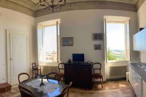 une salle à manger avec une table et des chaises et deux fenêtres dans l'établissement Casa Odda - Fermo Centro Storico, à Fermo