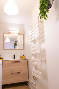 La salle de bains est pourvue de murs blancs, d'un lavabo et d'un miroir. dans l'établissement Joli nid douillet proche Nîmes, à Bouillargues