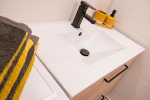 a bathroom sink with a black faucet and a yellow towel at Joli nid douillet proche Nîmes in Bouillargues