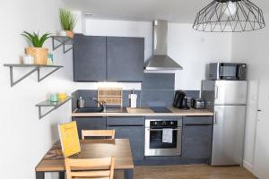 a kitchen with a table and a refrigerator at Joli nid douillet proche Nîmes in Bouillargues