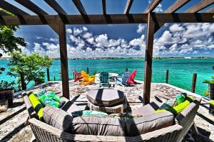 eine Terrasse mit einem Sofa und Stühlen am Strand in der Unterkunft Harbour Beach Villa - large dock & great views! in Marsh Harbour