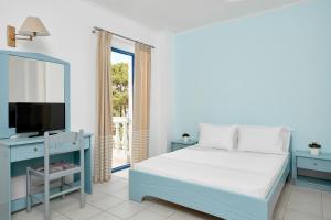a bedroom with a blue bed and a television at Kazaviti Hotel in Prinos