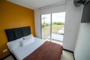 - une chambre avec un lit et une grande fenêtre dans l'établissement Apartamento con parqueadero, piscinas y wifi a 5 min del parque del café, à Montenegro