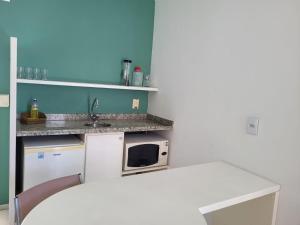 eine kleine Küche mit einer Spüle und einer Mikrowelle in der Unterkunft Praia do Canto Apart Hotel - Apto 405 - Varanda Lateral com Vista Mar in Vitória
