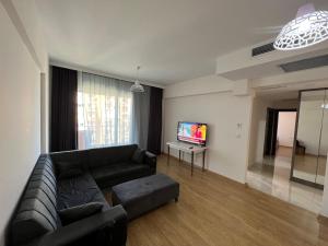 a living room with a black couch and a tv at Antalya apartment in Antalya