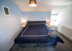 1 dormitorio con 1 cama grande y edredón azul en The Old Coach House, en Aberaeron